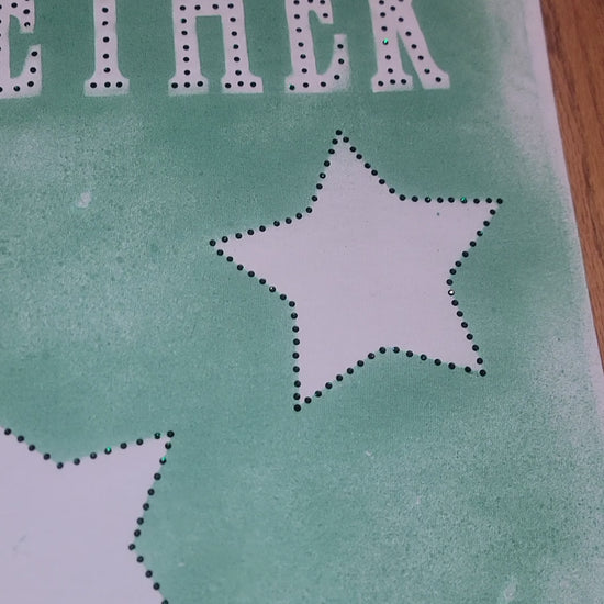 RISING STAR FABRIC-PAINTED TEE fabric design featuring green background and dotted stars.